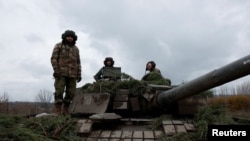 Украински войници се готвят да изстрелят снаряд от руски танк Т-80. Танкът е трофей на украинската армия, завзет още през март по време на битката при Тростанец, Украйна. Снимката е от района на Бахмут. 6 ноември 2022 г.