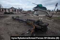 Oštećeni spomenik bici u Drugom svjetskom ratu između sovjetskih i nacističkih snaga stoji iznad olupine modernog oklopnog vozila u ponovno zauzetom gradu Trostjanka, u ukrajinskoj oblasti Sumy, u martu.