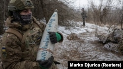 Un artilerist ucrainean din Brigada a 3-a de Asalt se pregătește să tragă un obuz de 152 mm cu inscripția „De la Ihor ca răzbunare pentru Mariupol”, în apropiere de Bahmut, 6 februarie.