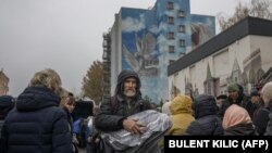 Banorë të Hersonit furnizohen me batanije dhe llamba në qendër të Hersonit, ku po shpërndaheshin ndihma më 17 nëntor, 2022.