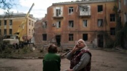 Raisa Smielkova, 75 de ani, privește pompierii care lucrează pentru a stinge un incendiu la o clădire rezidențială din Sloviansk, Ucraina, miercuri, 7 septembrie 2022. Smielkova dormea în momentul exploziei. „Ai fi un prost să nu te sperii de asta”, spune ea. 