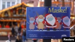 Жаңы жылдык жарманкеге келгендерге беткап тагынуу боюнча эскертме. Франкфурт, Германия. 22-ноябрь, 2021-жыл.