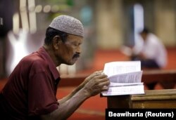 یک مسلمان اندونزیایی در حال مطالعه قرآن در مسجدی در جاکارتا