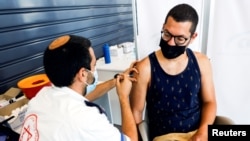 Egy izraeli férfinak adják be a harmadik oltást Tel-Avivban 2021. augusztus 30-án. Izrael a világon elsőként kezdte el a tömeges emlékeztetőoltásokat