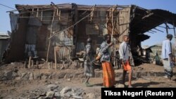 Ljudi stoje pored kuća uništenih u vazdušnom napadu tokom borbe između Etiopskih nacionalnih odbrambenih snaga i snaga Narodnog oslobodilačkog fronta Tigraj, 25. februara 2022.