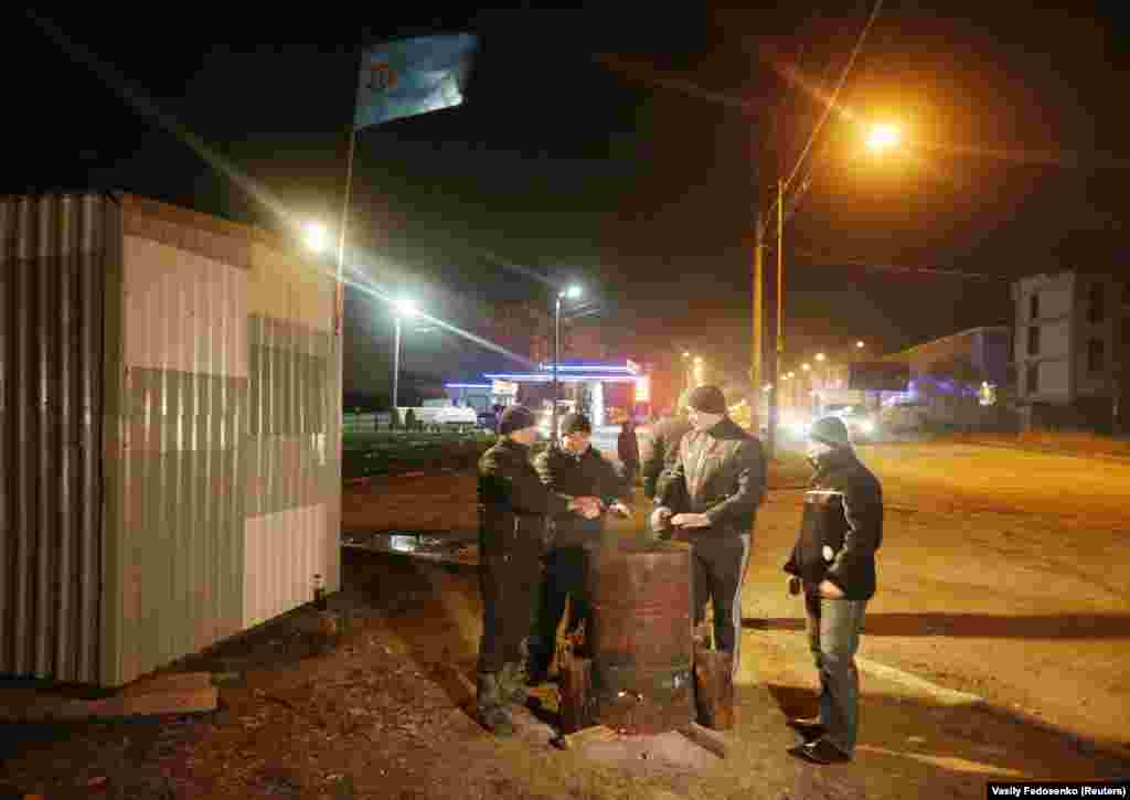 Кримські татари гріються біля багаття, охороняючи свій квартал, 9 березня 2014 року. Виконувач обов&#39;язків прем&#39;єр-міністра України Арсеній Яценюк пообіцяв, що Україна не віддасть &laquo;ні сантиметра&raquo; своєї території. На той час захоплення Криму Росією закріплювалося, а життя місцевих жителів, які виступати проти окупації півострова, ставало дедалі небезпечнішим