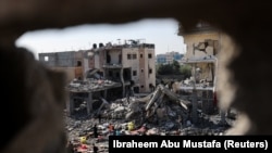 Palestinci stoje među ruševinama kuća uništenih u izraelskom napadu, usred privremenog primirja između Hamasa i Izraela, u Kan Younisu u južnom pojasu Gaze 24. novembra 2023.