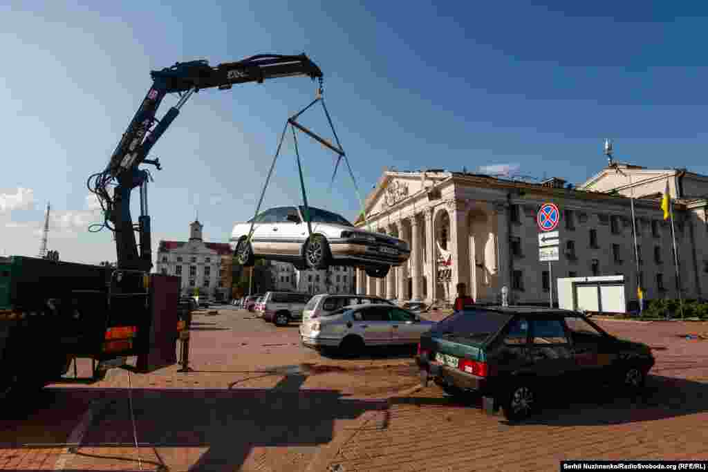 Krhotine su razbacane po trgu ispred pozorišta, gdje su parkirani automobili teško oštećeni.