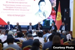 Насирдин Исановдун 80 жылдыгына арналган илимий жыйындын төрүндө отургандар. Солдон биринчи – Мамлекеттик катчы Сүйүнбек Касмамбетов. Жанында – постсоветтик Жогорку Кеңештин алгачкы төрагасы Медеткан Шеримкулов. ОшМУ, Ош шаары. Кыргызстан. 31.8.2023.