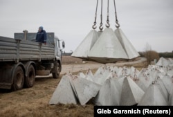 Робітник встановлює «зуби дракона» біля кордону з Росією в Чернігівській області, 28 березня 2024 року