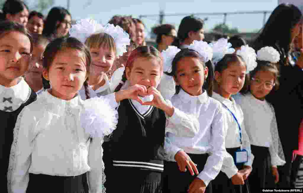 Egy kislány szívet formál a tudás napja alkalmából rendezett ünnepségen egy kirgizisztáni iskolában szeptember 1-jén
