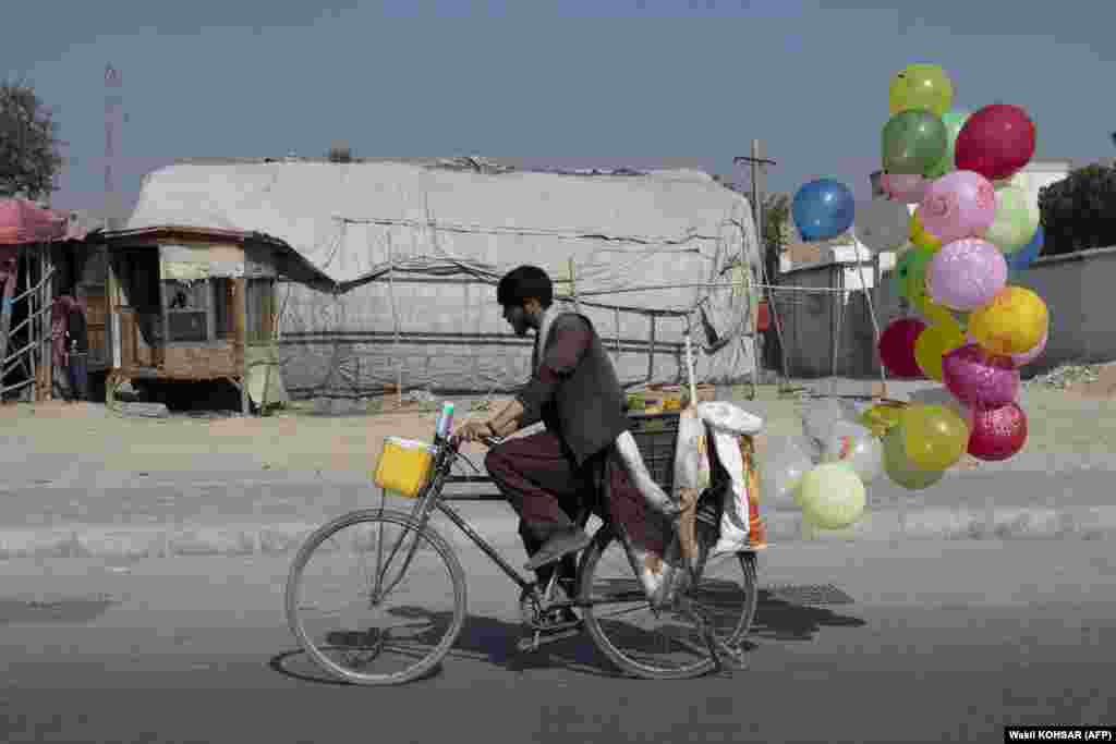 Un vânzător afgan de baloane se plimbă cu bicicleta pe o stradă din Kabul, 31 august, 2023.