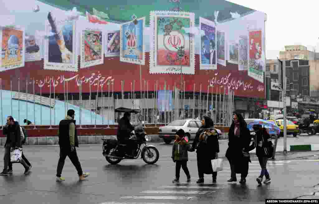 În Piața Revoluției din Teheran, iranienii trec pe lângă un panou publicitar pe care se află o propoziție în persană pe care scrie &quot;Spune Nu! la orice, cu excepția Republicii Islamice Iraniene&quot; și &bdquo;Am spus da! Republicii Islamice Iraniene&quot;.