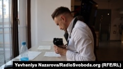 Сергій Звілінський фотографує родинні документи, які вимушені переселенці принесли на захід очолюваного ним історичного товариства