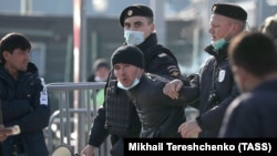 Российская полиция ведет иностранного гражданина в центр временного содержания. Иллюстративное фото.