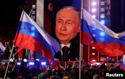 Выступление Владимира Путина транслируется на экране в Москве. Россия, 18 марта 2024 года