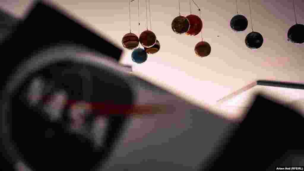 Небесни тела висат од таванот во близина на еден од донираните телескопи, на кој стои логото на НАСА.