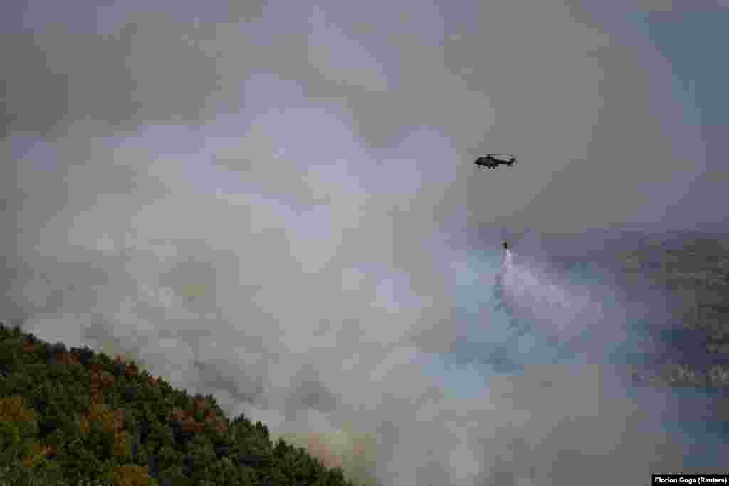 Helikopteri zjarrfikës duke bombarduar me ujë flakët në një pyll afër Cakranit.