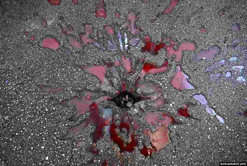 Komad minobacačke granate još uvek zabijen u beton, na sarajevskoj pijaci tokom komemoracije povodom obeležavanja 30. godišnjice prvog od dva masakra na Markalama, u kojem je granata koju su ispalile snage bosanskih Srba ubila 68 i ranila 144 ljudi 5. februara 1994. tokom opsade Sarajeva.