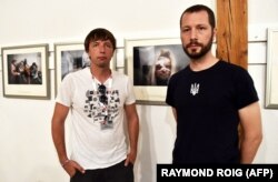 Українські фотографи Євген Малолєтка (ліворуч) і Мстислав Чернов позують перед своїми фотографіями на виставці «Маріуполь, Україна» під час Міжнародного фестивалю фотожурналістики Visa pour l'Image. Місто Перпіньян, Франція, 31 серпня 2022 року