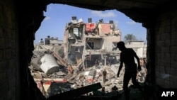 Младеж стои пред дупка в стена на сграда, ударена при израелска бомбардировка в Хан Юнис в южната част на Ивицата Газа. Междувременно израелската армия съобщи, че провежда сухопътна операция "в сърцето на Газа", 8 ноември 2023 г.