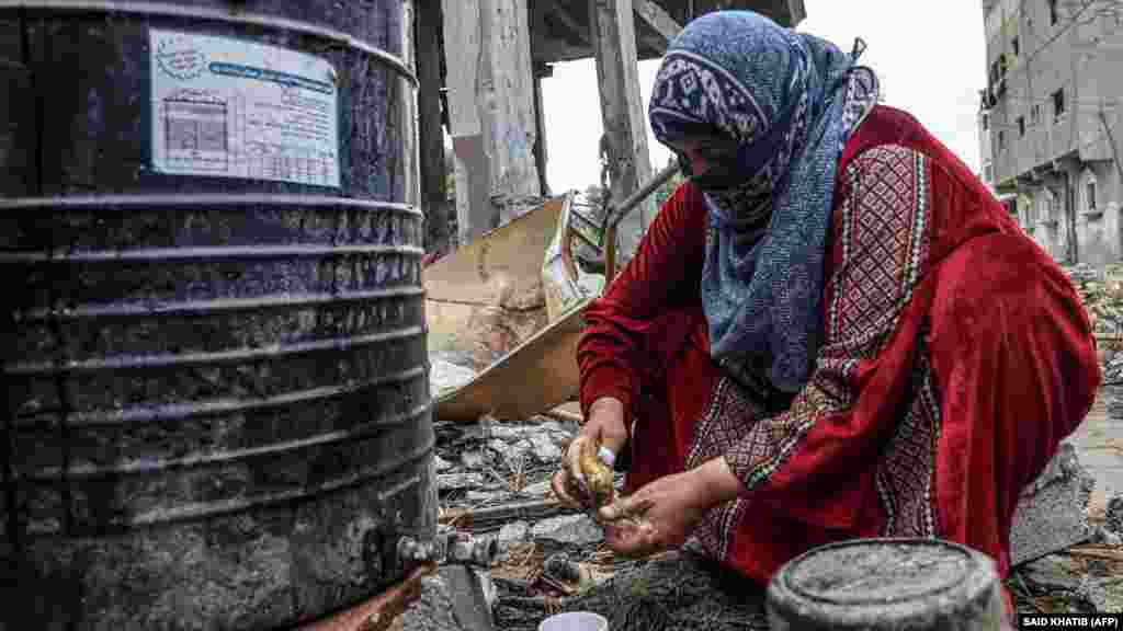 Egy palesztin nő edényeket tisztít az izraeli támadások okozta pusztítás után a Gázai övezet déli részén 2023. november 27-én.&nbsp;Legalább tizenötezer ember, főként civilek haltak meg Izrael gázai katonai manőverei során, miután a Hamász&nbsp;palesztin&nbsp;terrorszervezet 2023. október 7-én megtámadta&nbsp;az országot