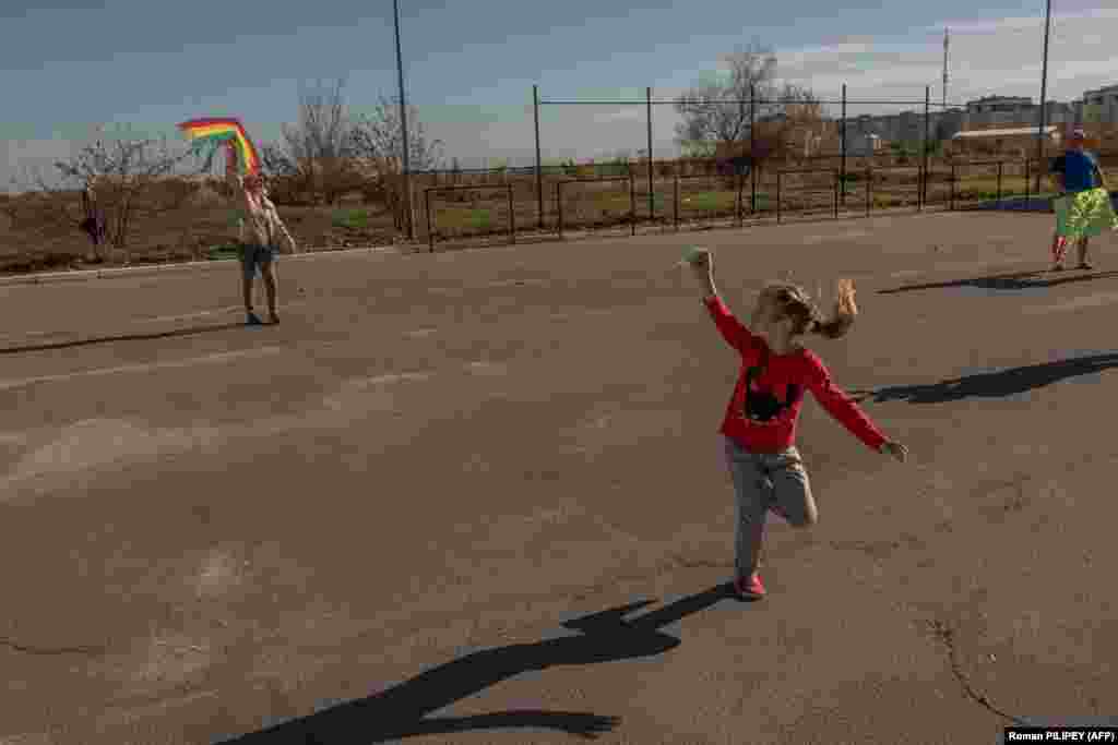 Djevojčica pušta zmaja sa bakom na kasnom poslijepodnevnom suncu u Hersonu.