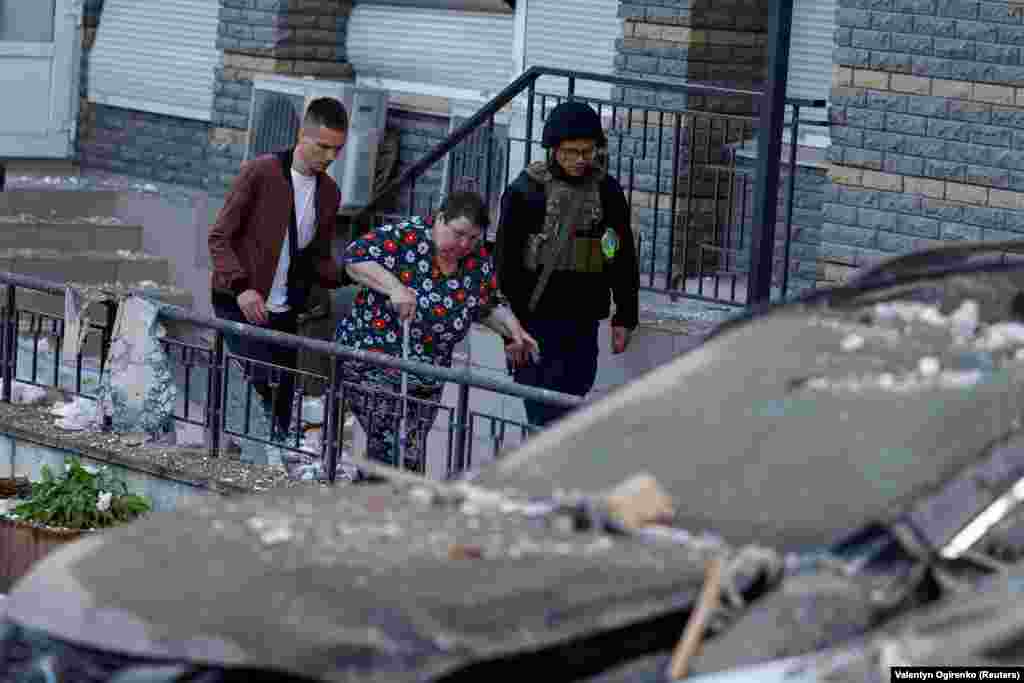 Muškarci pomažu ženi da izađe iz oštećene zgrade.&nbsp;