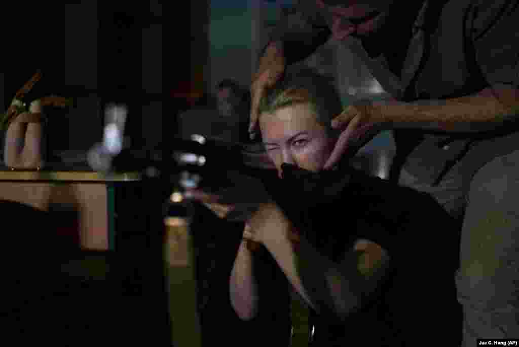 Instruktor prilagođava držanje žene koja drži pušku AK-47 tokom obuke upotrebe vatrenog oružja. &quot;Glavni cilj je da ljudi nauče kako da prežive i kako da odgovore na ove vojne pretnje koje postoje&quot;, objasnio je Ščerbina. Lokalne vlasti se nadaju da će edukacijom ljudi sprečiti više žrtava u budućnosti.