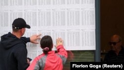 Dy votues në Tiranë duke kërkuar emrin e tyre në listën e votuesve. Shqipëri, 14 maj 2023.