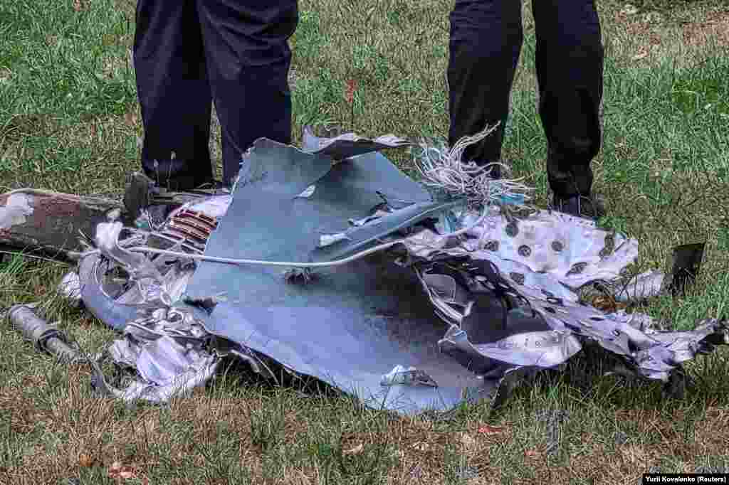 Ukrajinski policajci stoje pored krhotine rakete u parku nakon ruskog napada na Kijev.