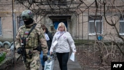 Украинанын Донецк облусунун Орусия басып алган аймактарында шайлоо комиссиясынын мүчөлөрү аскерлердин коштоосунда үйлөрдү кыдырып жүрүшөт. 14-март, 2024-жыл.