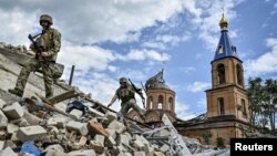 Soldați ucraineni patrulează o zonă avariată de loviturile militare rusești în orașul Orikiv din regiunea Zaporojie. 20 mai 2024.