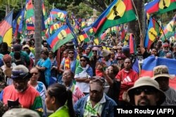 Protestatarii fluturează steaguri ale Frontului Socialist Kanak de Eliberare Națională (FLNKS) în timpul unei demonstrații împotriva lărgirii electoratului pentru viitoarele alegeri provinciale din Noua Caledonie, la Noumea, pe 13 aprilie 2024.