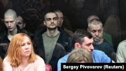 На задньому плані (за склом) ув’язнені українські громадяни в суді у російському Ростові-на-Дону, більшість із них – військовополонені, бійці полку «Азов». Росія, Ростов-на-Дону, 14 червня 2023 року