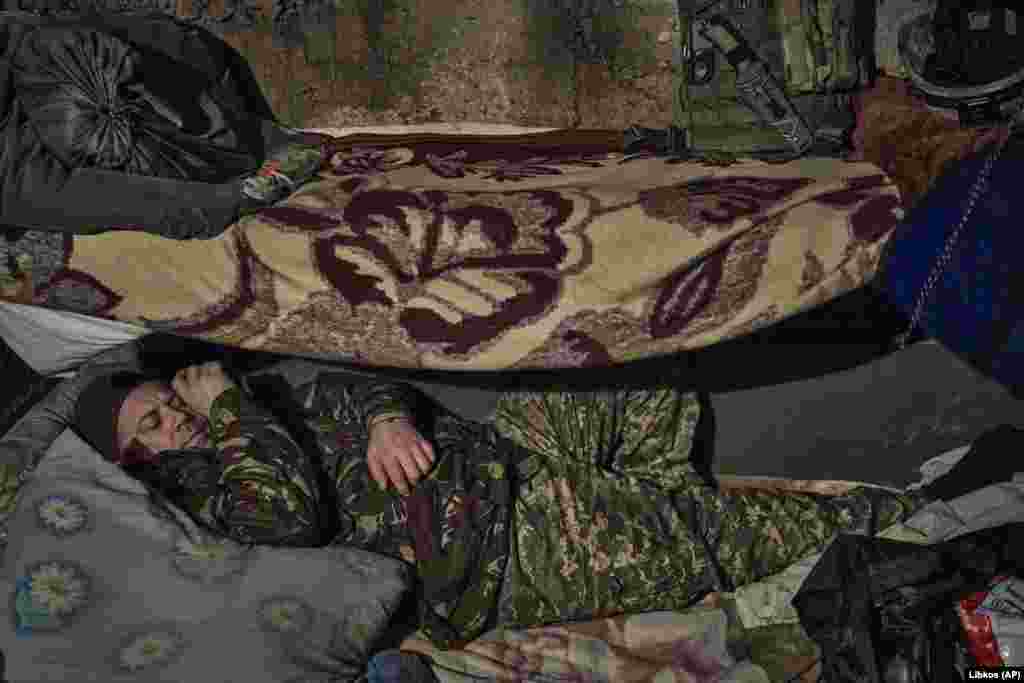 Un soldat ucrainean se odihnește într-un adăpost pe linia frontului.