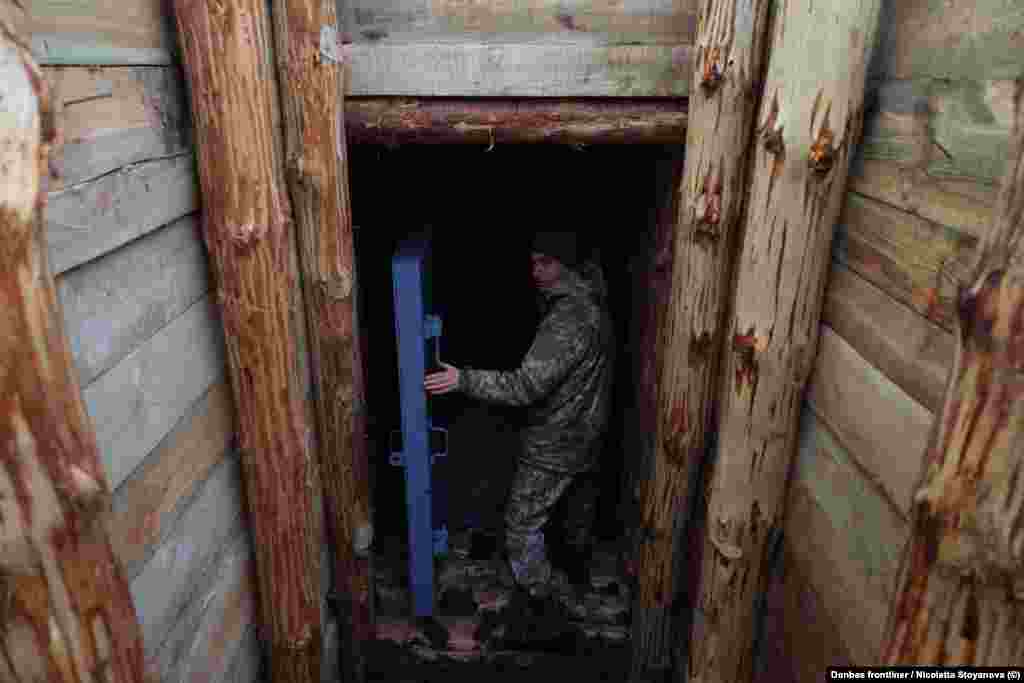 Військовослужбовець заходить до бетонного бункера, вбудованого в систему траншей на Сумщині.