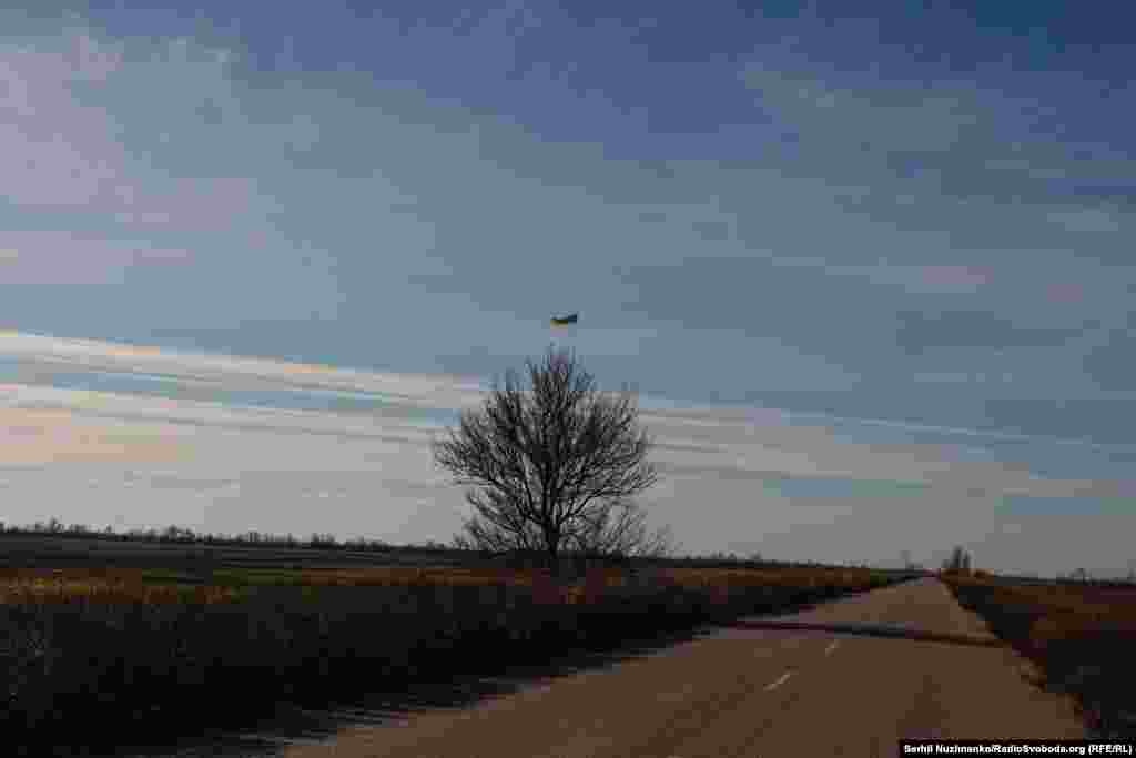 Звільнена територія Миколаївщини. Жовтий шлях під синім небом і український прапор на дереві. Листопад 2022 року&nbsp;