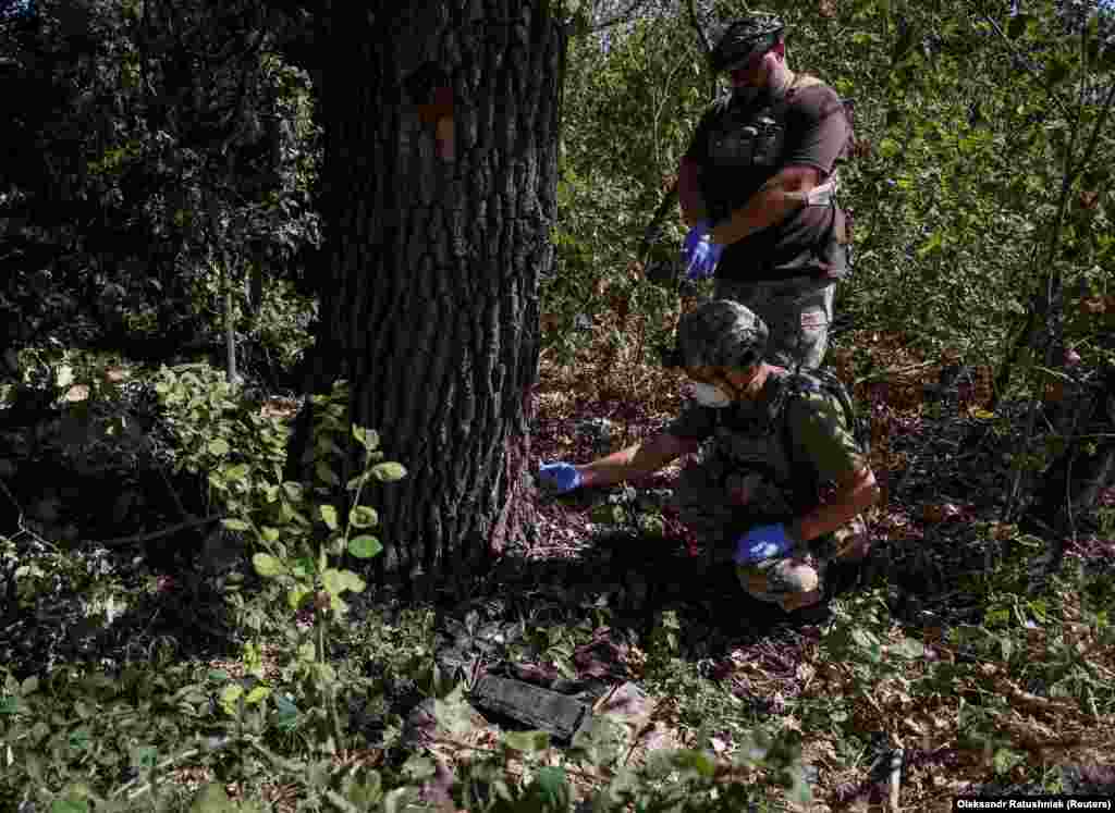 Volodomir pažljivo ispituje telo mrtvog ruskog vojnika 8. septembra dok njegov kolega posmatra sa strane. &quot;Njihovo ratno ime i svaku drugu identifikaciju stavljamo na njihova tela. Lakše je zameniti identifikovanu osobu za naše vojnike&quot;, rekao je on.