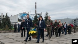 Служители в нефункциониращата АЕЦ Чернобил полагат цветя пред паметник на загиналите при аварията преди 37 години.