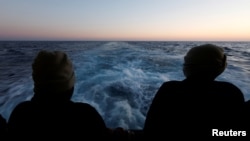 Spašeni migranti gledaju na pučinu sa spasilačkog broda Geo Barents, kojim upravljaju Ljekari bez granica, dok se brod kreće prema italijanskoj luci Bari, 25. mart 2023.