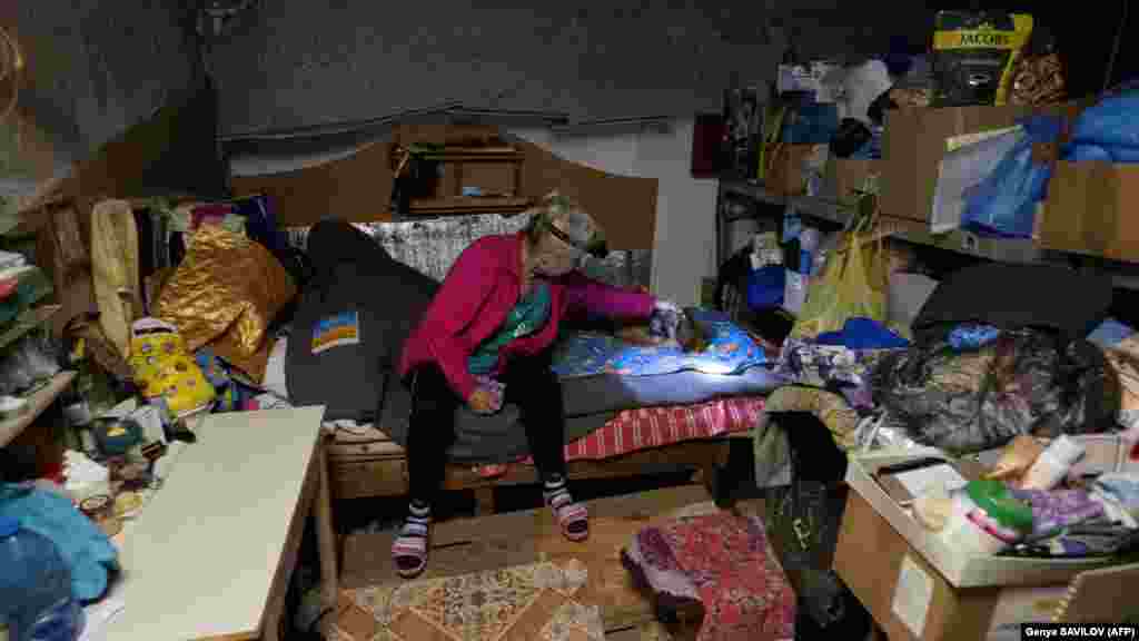 Egy idős nő és kutyája egy pincében, ahol élnek.