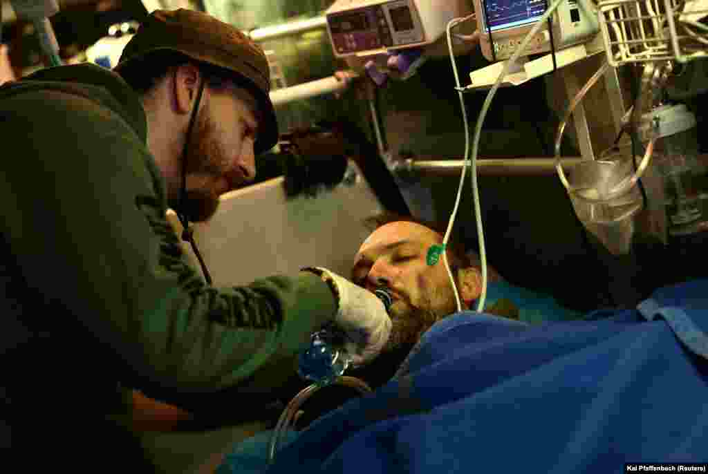 Ruszlan, egy 26 éves önkéntes mentős itat egy ukrán katonát, aki megsebesült Bahmutban