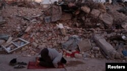 Stanovnik Kahramanmaraša moli se ispred sravnjene zgrade, 14. februar 2023. godine.