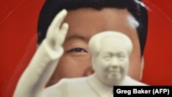 Кытайдын Коммунисттик партиясынын биринчи төрагасы Мао Цзэдундун айкелинин артында өлкөнүн азыркы лидери Си Цзинпиндин сүрөтү турат. Иллюстрациялык сүрөт.