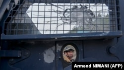 Pripadnik specijalne jedinice policije Kosova iza armiranog vozila pogođenog mecima u blizini manastira u Banjskoj, sever Kosova, 27. septembar 2023. 