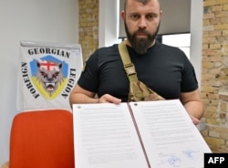 Мамука Мамулашвілі тримає папку з угодою про дотримання міжнародних норм щодо учасників бойових дій. Київ, 30 червня 2022 року