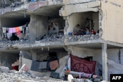 Palestinac i njegova djeca sjede u uništenoj zgradi nakon granatiranja zgrade u izraelskom zračnom napada u Rafahu, u južnom pojasu Gaze 22. maja 2024.