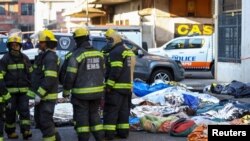 Өрт өчүрүүчүлөр имараттын ичинен алып чыккан сөөктөрдүн жанында турушат. Йоханнесбург, Түштүк Африка. 31-август, 2023-жыл. 