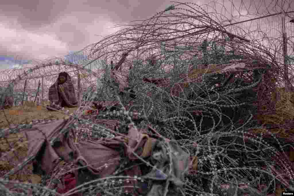 Hendri, 26, një emigrant nga Venezuela, qëndron i mbështjellë me një batanije për t&#39;u mbrojtur nga moti i ftohtë dhe i turbullt, ndërsa kërkon një pikë për t&#39;u futur në SHBA, duke kaluar një gardh të ngritur me tela me gjemba përgjatë bregut të lumit Rio Grande në El Paso, Teksas, SHBA, 25 mars 2024.